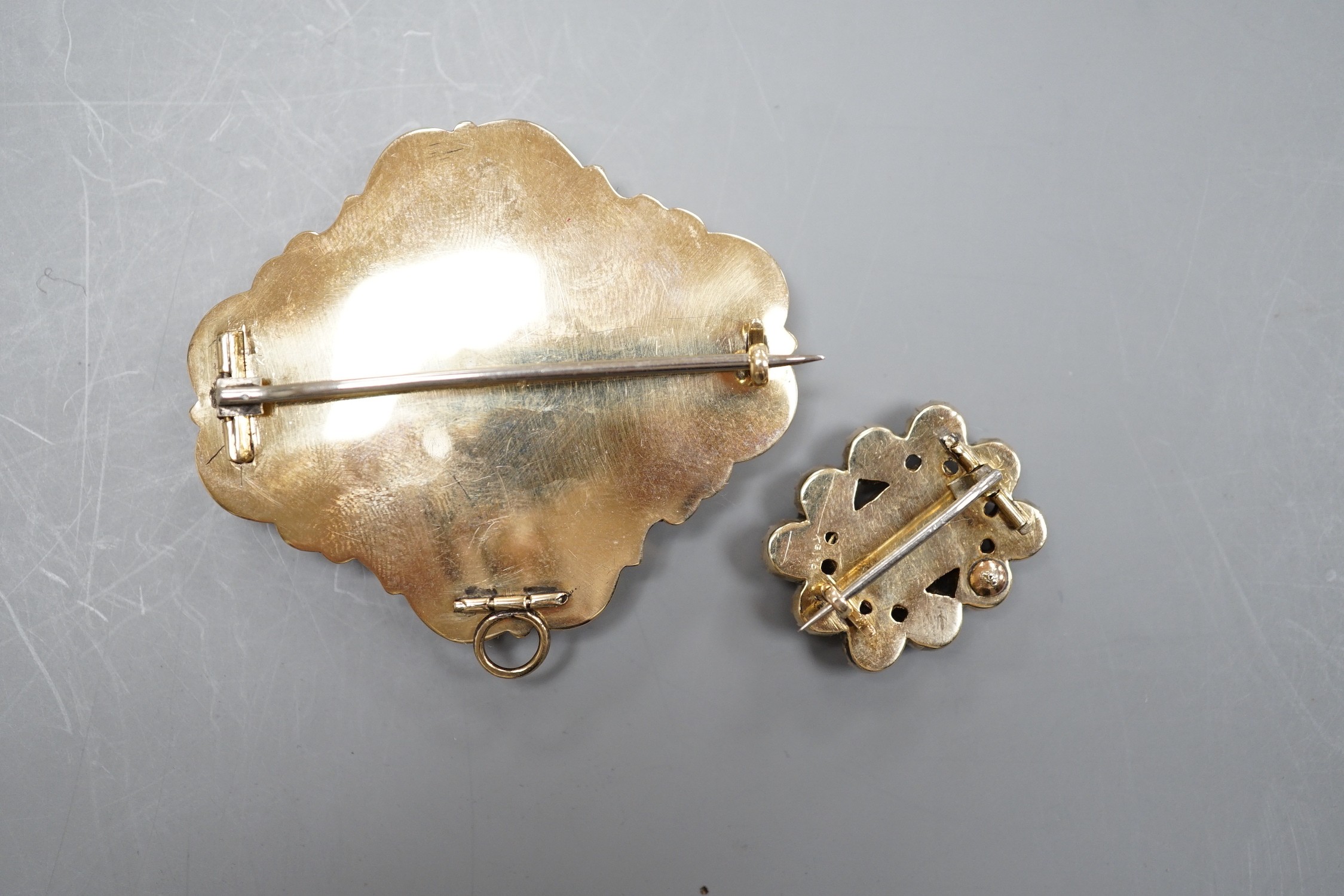 Two Victorian yellow metal (tests as 9ct) mourning brooches, one with black enamel and pendant bale, 51mm, the other with amethyst and seed pearl, both with plaited hair beneath a glazed panel.